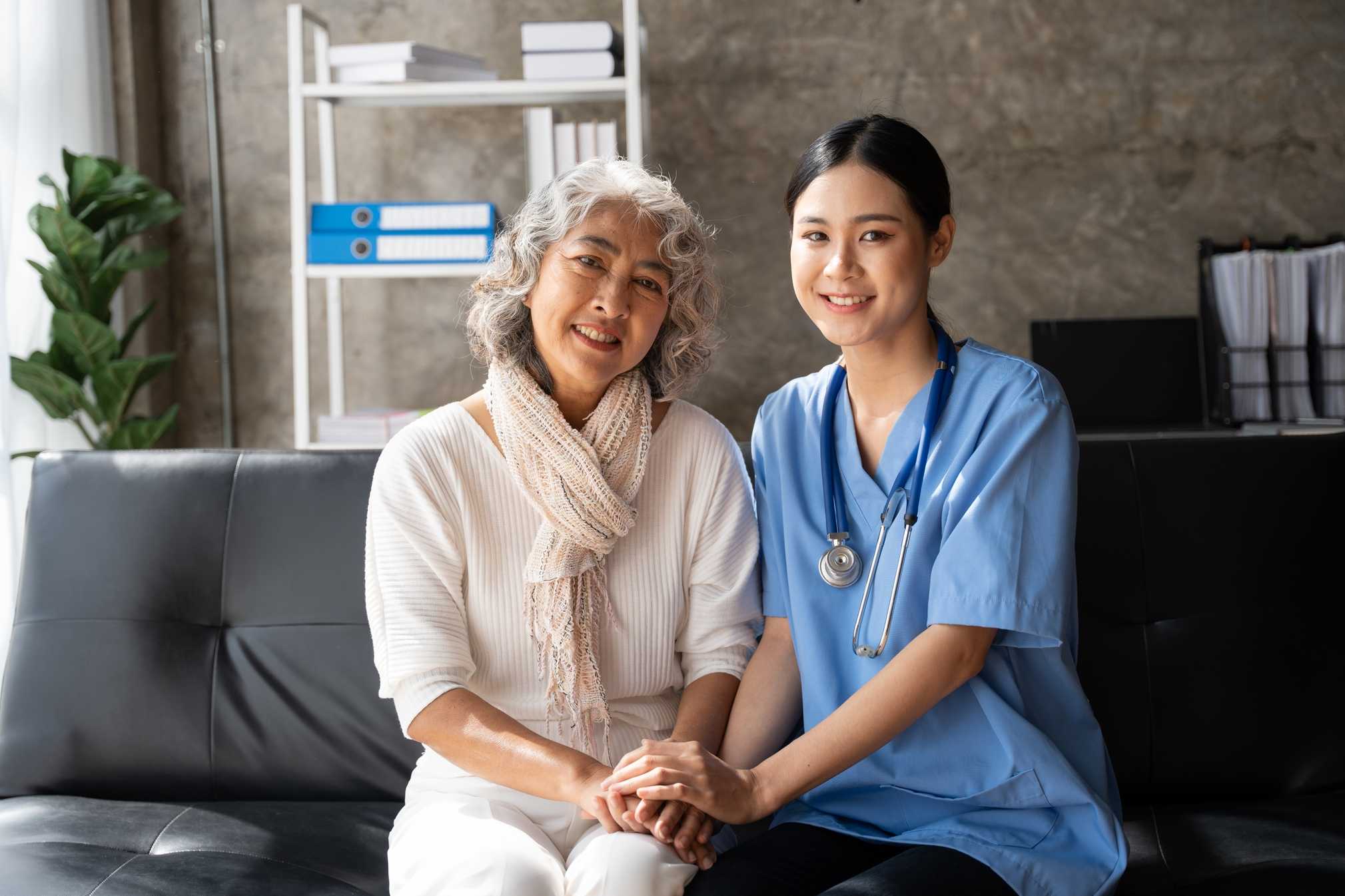 Asian nurse supporting an elderly patient at home